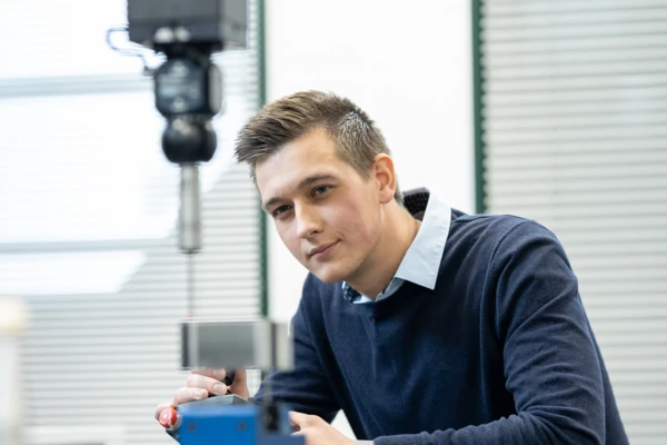 Ein junger Mann in einem Labor konzentriert sich auf ein Messinstrument zur Analyse von Pumpen und Systemen.