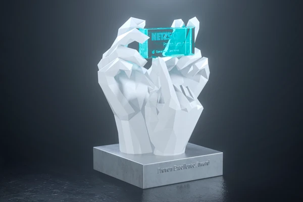 Weiße, stilisierte Hände präsentieren einen transparenten Preis mit der Gravur „NETZSCH Proven Excellence Award“ auf einem Sockel.