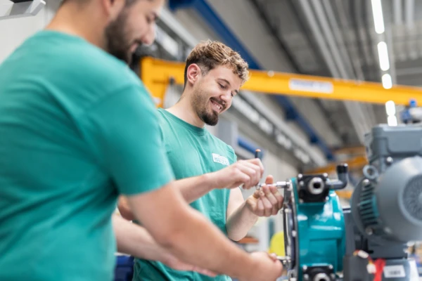 Un técnico con equipo de seguridad suelda componentes metálicos en una fábrica, centrándose en la precisión de la mano de obra.
