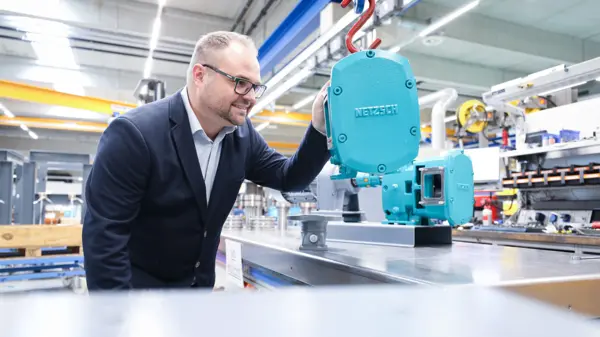 Stefan Schöberl inspecte une pompe à lobes rotatifs NETZSCH dans un environnement de fabrication lumineux, mettant en valeur l'ingénierie innovante.
