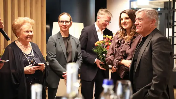 Michael Sigl est fêté pour ses 40 ans de service chez NETZSCH, entouré de ses collègues et tenant un bouquet de fleurs.