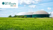 Planta de biogás renovable con grandes digestores bajo un cielo azul en un campo agrícola verde, Salón del Gas Renovable 2026.