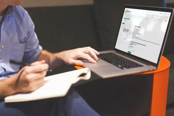 Person using a laptop to browse MyNETZSCH digital customer portal for ordering pump spare parts and accessing technical data.