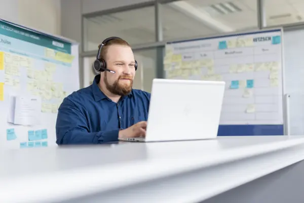 NETZSCH Kundenservice-Mitarbeiter berät kompetent zu Original-Ersatzteilen für industrielle Pumpen per Headset am Laptop.