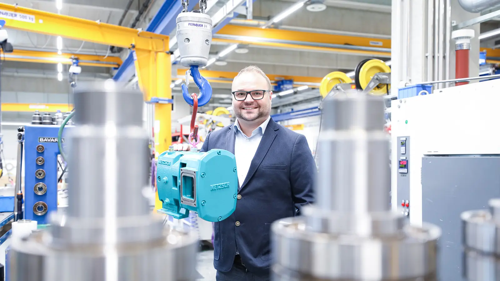 Stefan Schöberl tient une pompe à lobes NETZSCH dans une usine de fabrication, présentant des solutions de pompage innovantes.