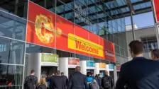 Folla all'ingresso di Messe München, con un grande striscione "Welcome Ceramitec" e saluti in lingua colorata.