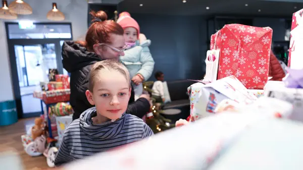 Les enfants choisissent avec empressement des cadeaux dans un arbre à souhaits magnifiquement décoré, apportant ainsi la joie et l'espoir de Noël aux personnes dans le besoin.