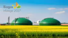 Green biogas storage tanks in a yellow flowering field under a clear blue sky, promoting Biogas Infotage 2027 event.